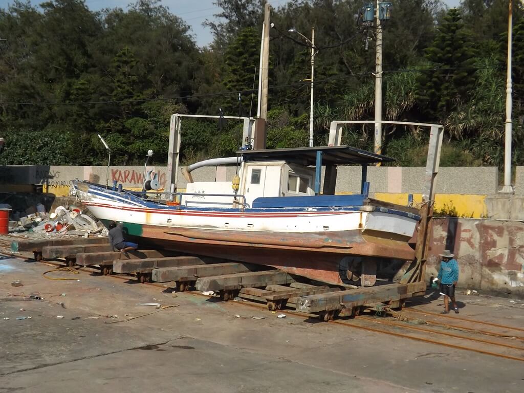 永安漁港的圖片：工作人員正在替漁船底部塗上新著漆