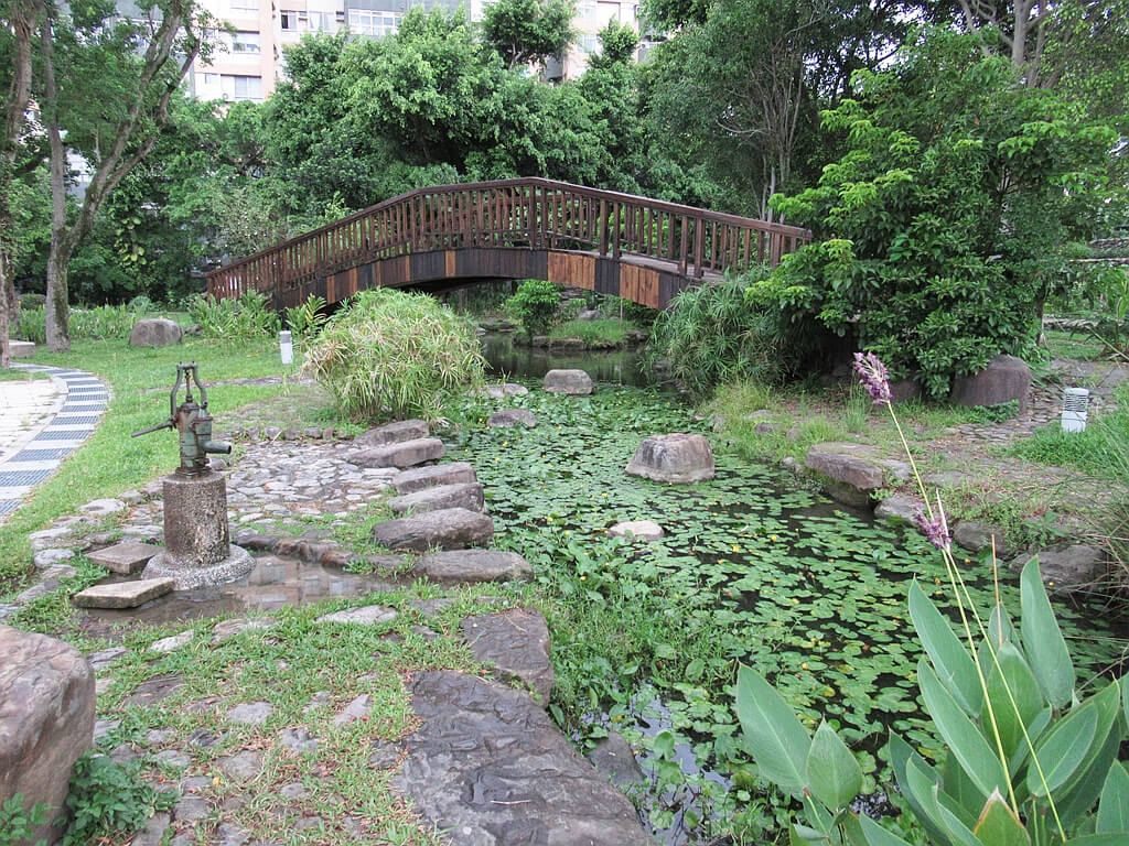 臺北市客家文化主題公園的圖片：手壓取水器、水池與木橋