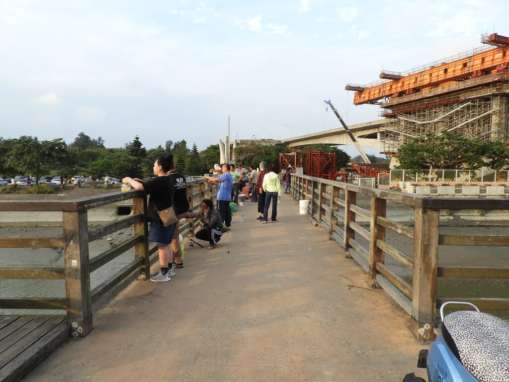 新豐紅樹林生態保護區的圖片：紅樹林橋上有許多人在釣魚