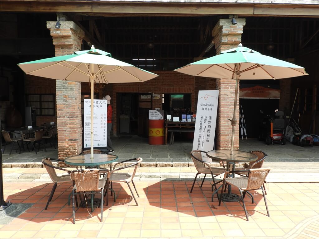 淡水文化園區 - 殼牌倉庫的圖片：服務中心外的兩組陽傘座位